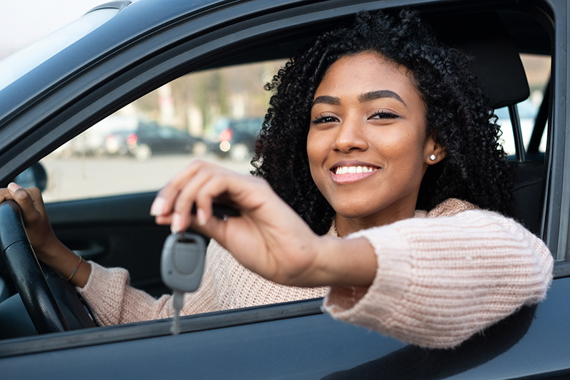 Happy young woman showing the keys of her new car
