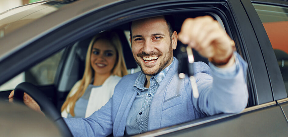 Young couple holding the keys of a new car.