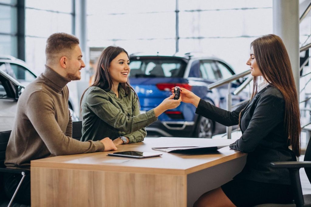A woman handing car keys to a buyer