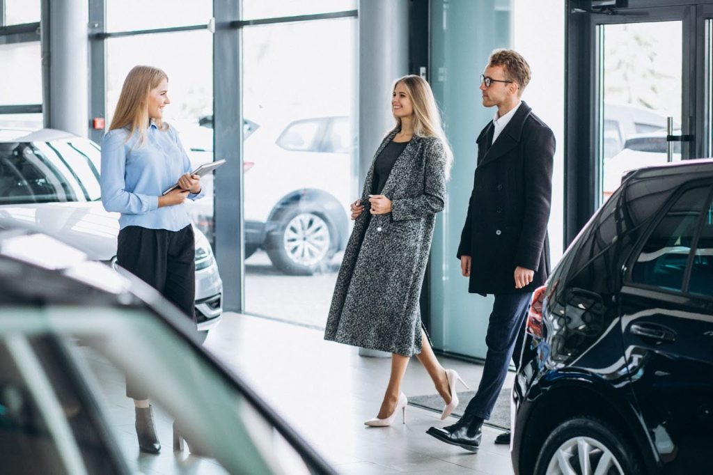 A dealer showing a car to a couple