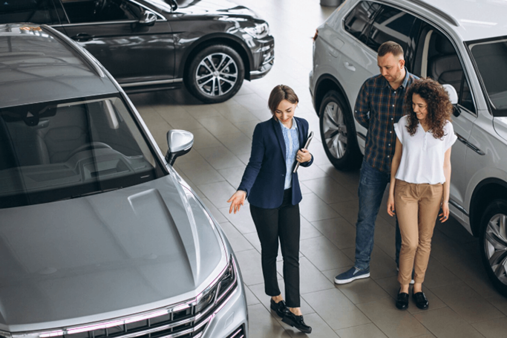 A car saleswoman showing a used car to the couple