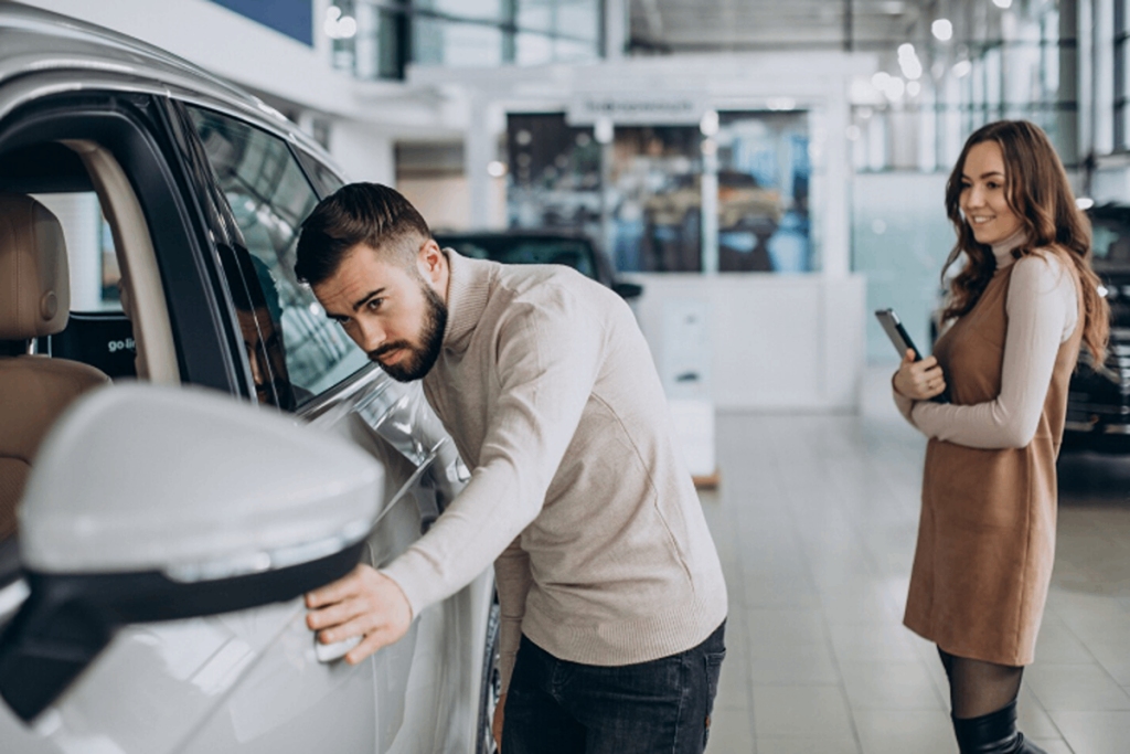 A man inspecting a used car he wants to buy.