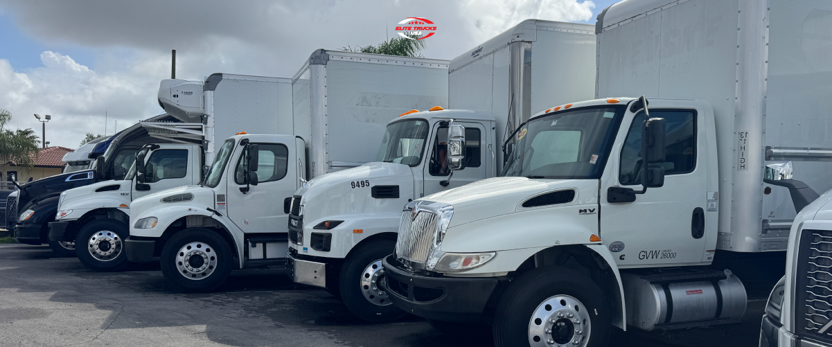 White commercial box trucks parked in a lot.
