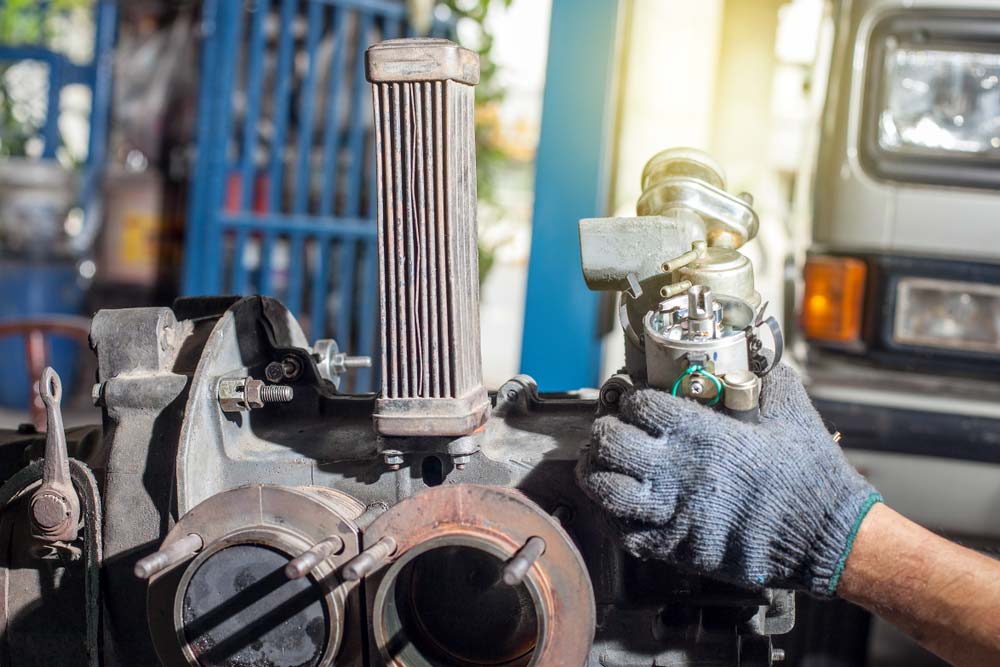 engine-repair Car engine repair with technician holding carburetor at Qwest Automotive Service Las Vegas NV