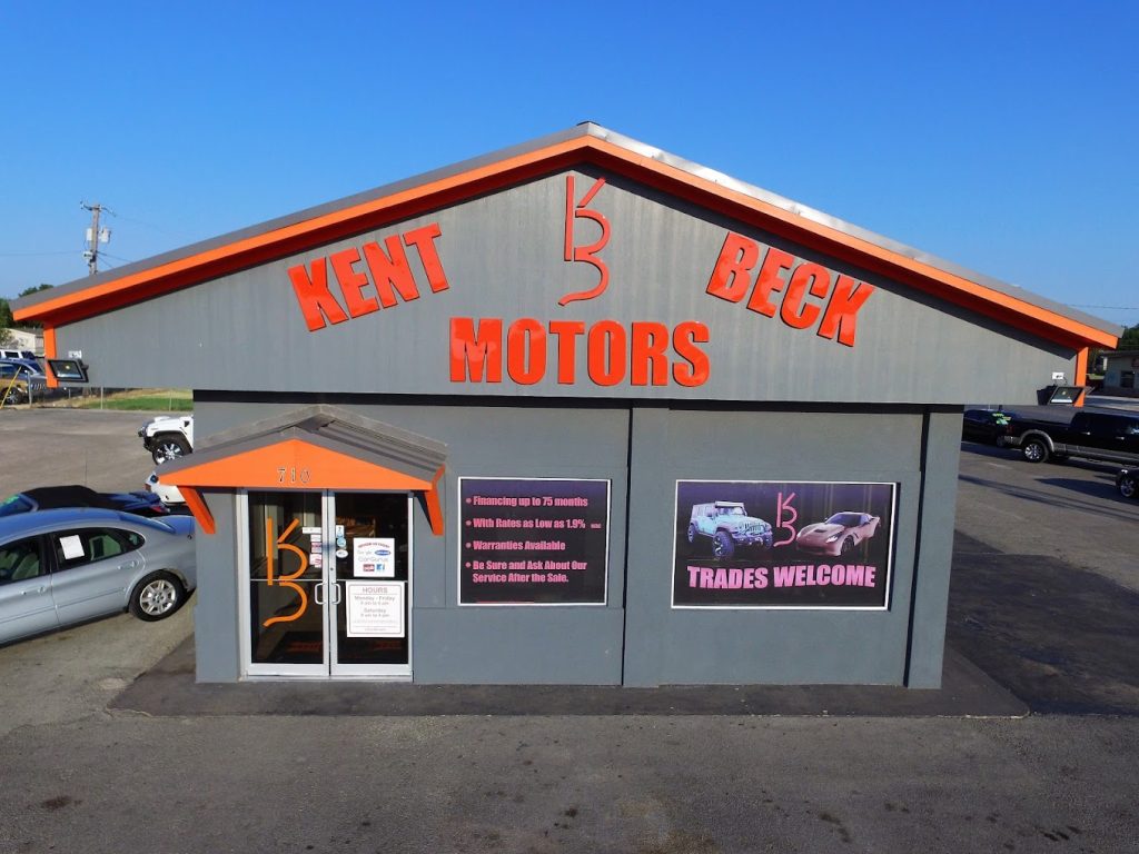 Kent Beck Motor's one of the best carlots in Abilene, TX with a grey building and orange bold text
