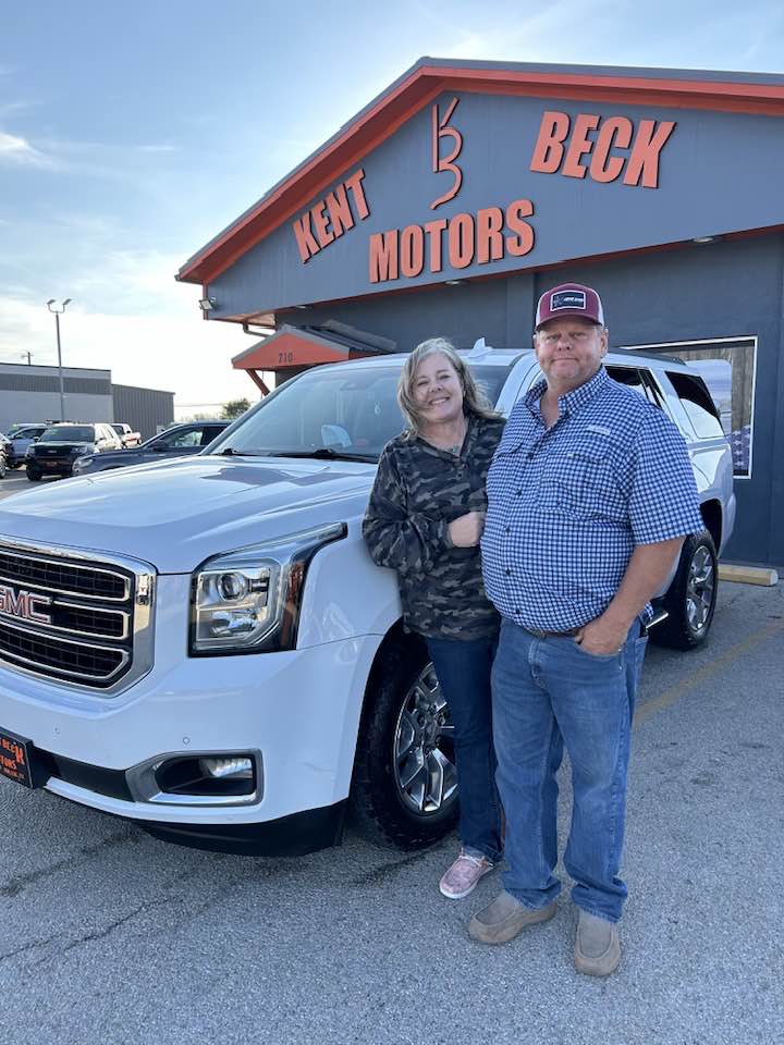 Happy couple after doing a car trade in Abilene, TX standing in front of Kent Beck Motors
