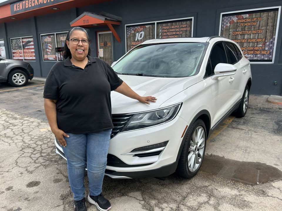 Happy customer standing next to her SUV after buying a quality used car in Abilene at Kent Beck Motors.