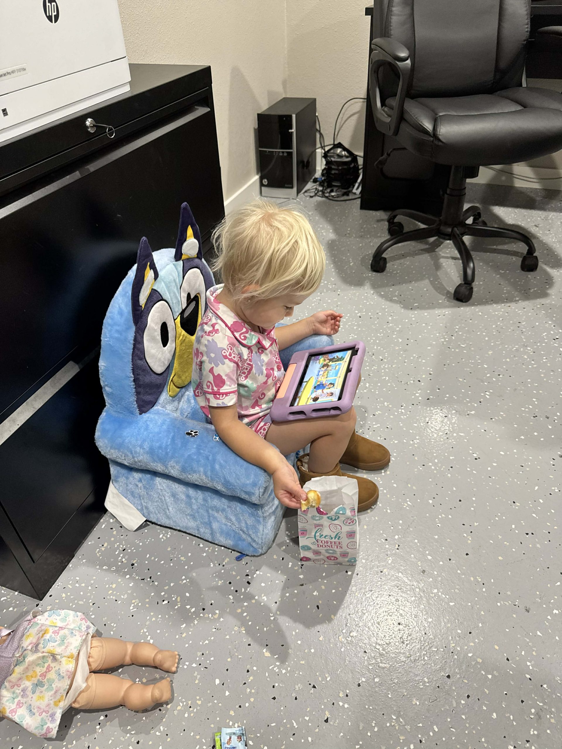 Toddler sitting on a kids’ cartoon chair inside Dollar Sharp Motors