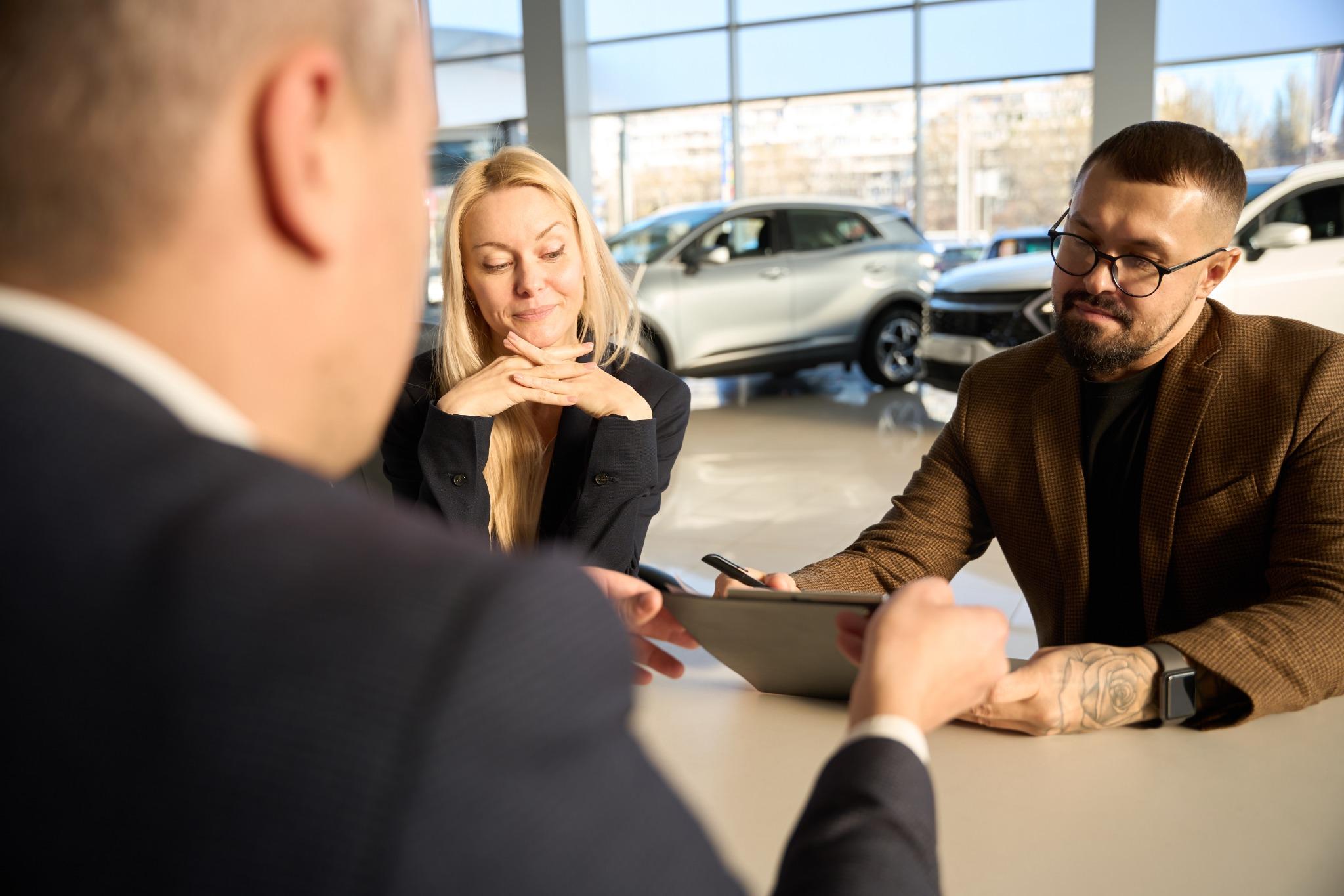Couple reviewing paperwork for a buy here pay here used car at a dealership