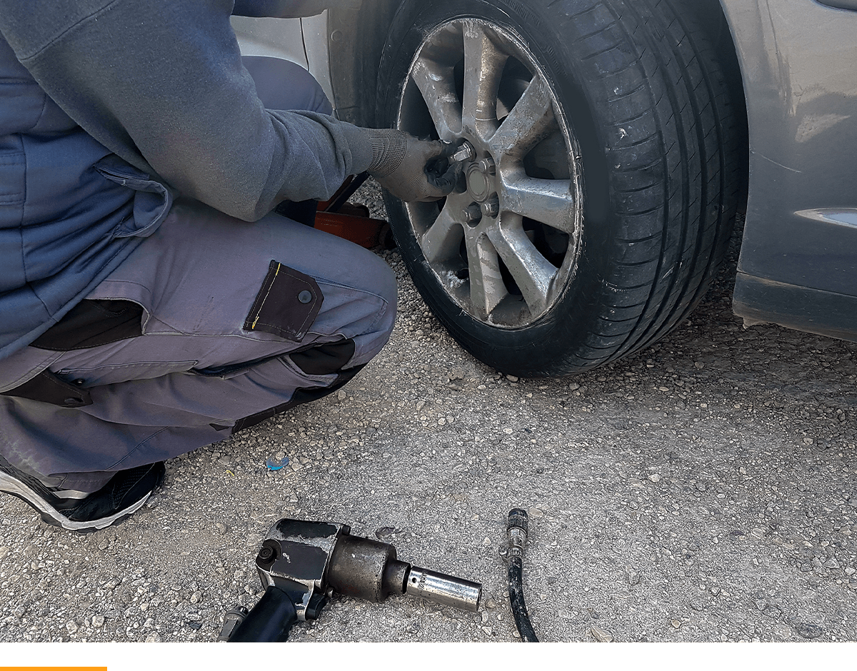 Person kneeling down, changing a tire. 
