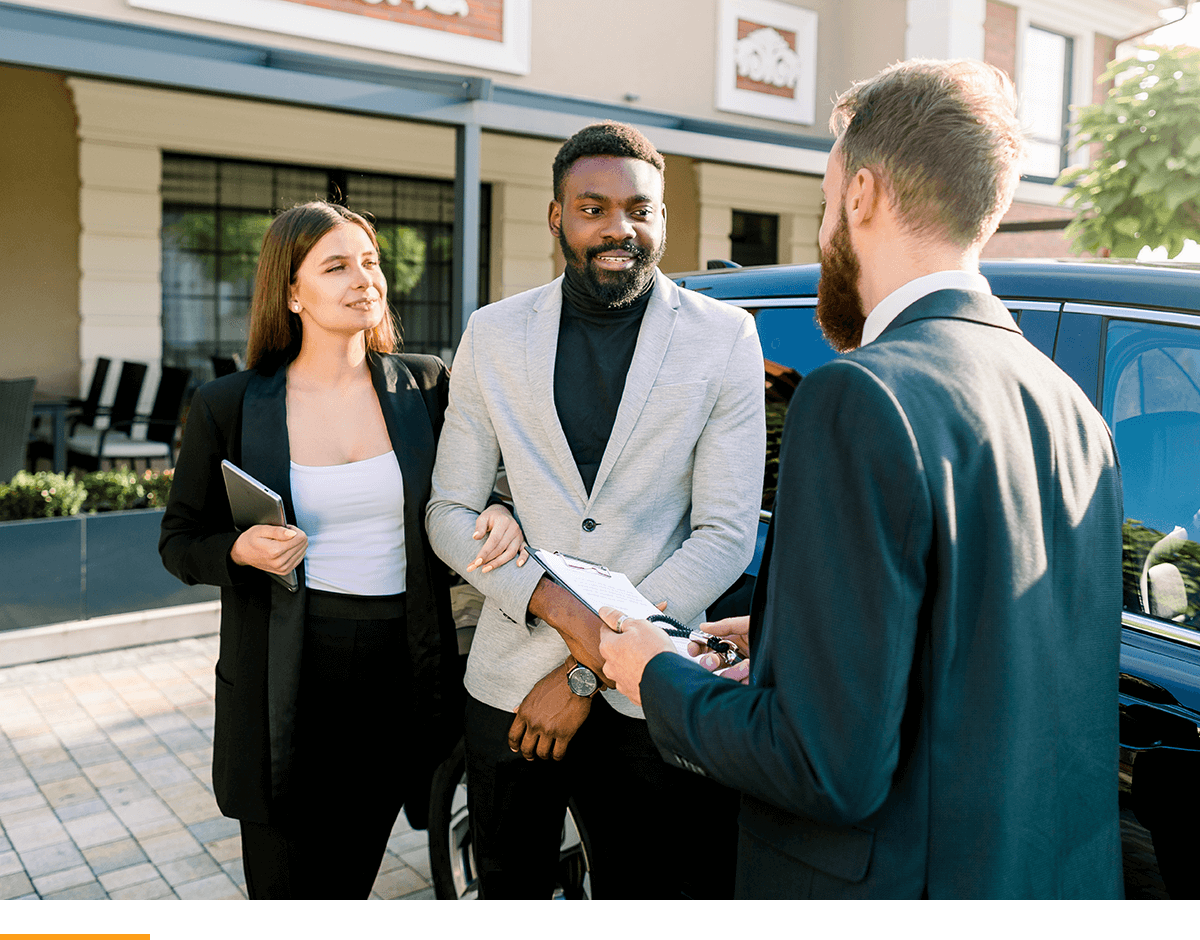 A used car dealer discussing terms with a man and a woman. 