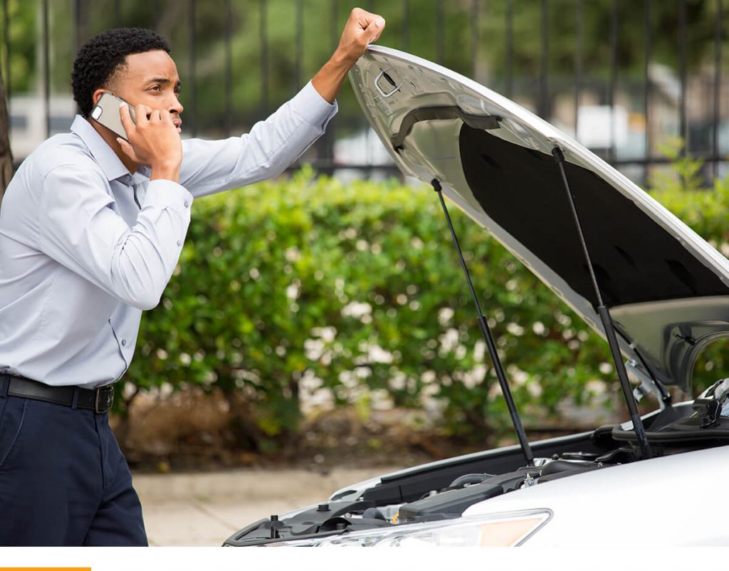 Man on the phone, leaning up against the hood of his broken down car. 