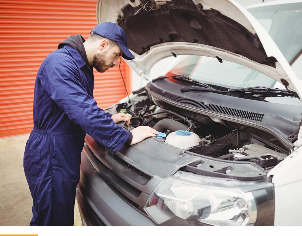 Man in navy blue looking under the hood of a car at the fluids.