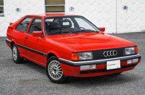 Classic red Audi Quattro coupe with silver multi-spoke wheels and black trim.