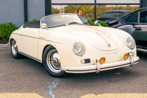 Classic cream-colored Porsche Speedster convertible with chrome accents and a black soft top.