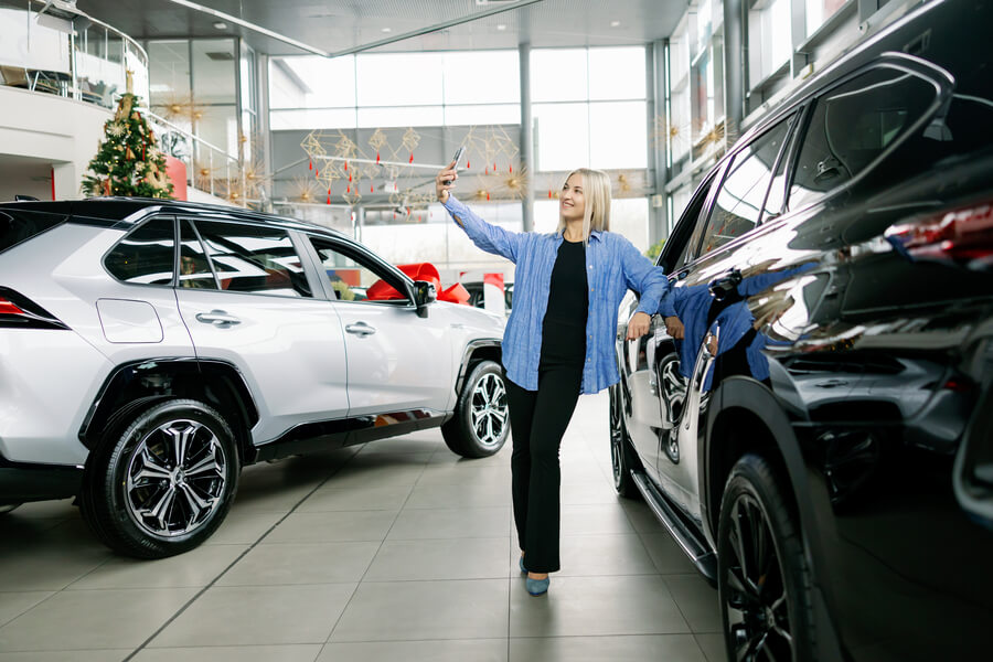 Customer touching a car while walking through a dealership showroom.