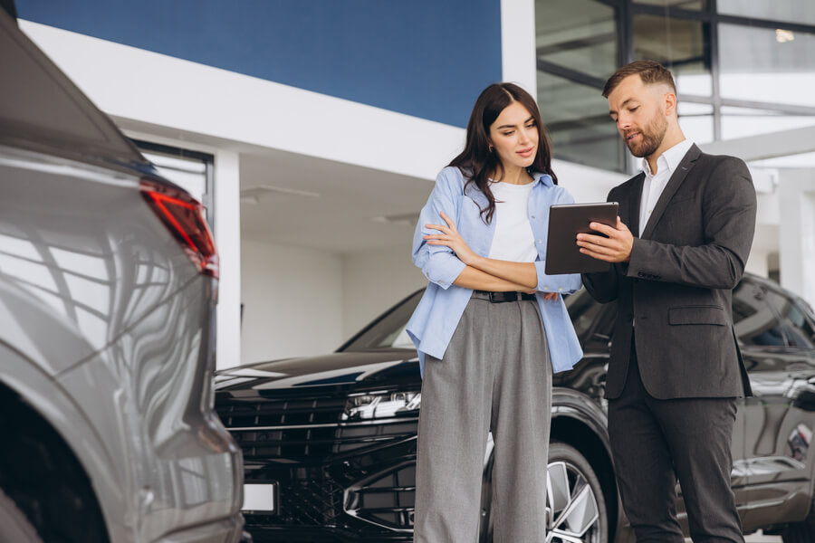 income tax refund advance - Salesperson explaining car details to a customer in a showroom.