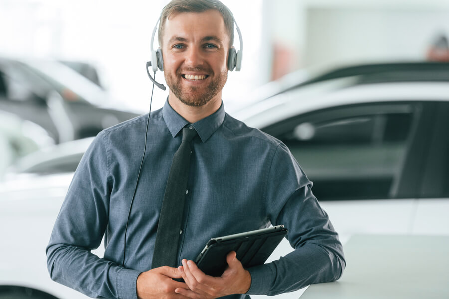 Miami dealer used cars - Customer service agent wearing a headset in a car showroom