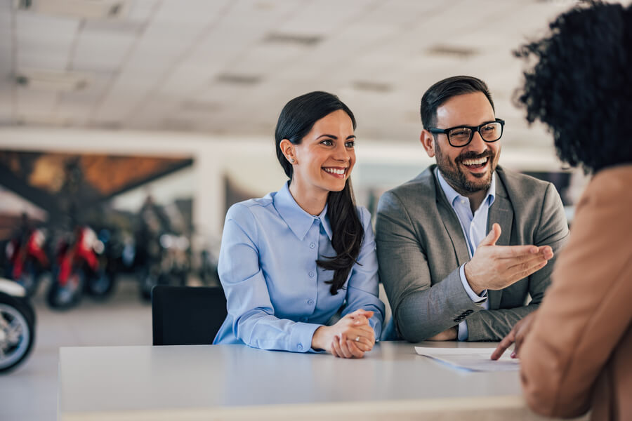 Miami dealer used cars - Couple talking with a salesperson in a showroom.