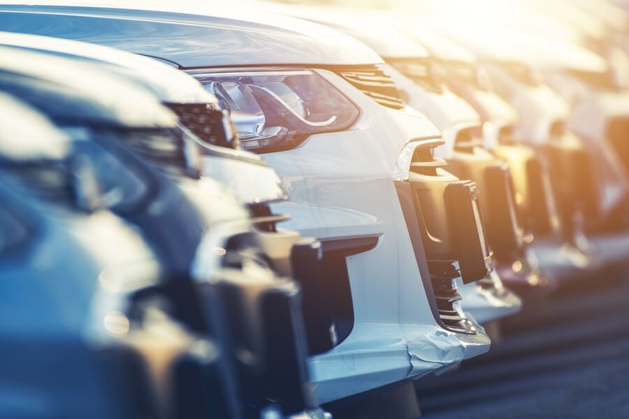Row of cars parked outdoors at a dealership during sunset.