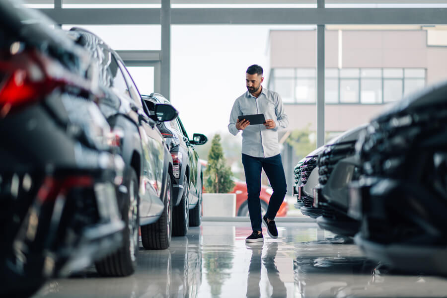 Man walking between cars inside a dealership showroom.