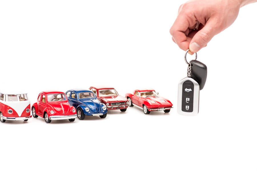 Income tax refund - Hand holding car keys next to toy cars.