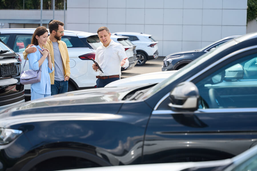 Income taxes florida - Salesperson showing cars to a couple outdoors.