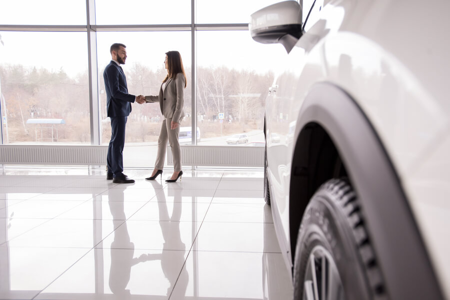 Income taxes florida - Sales agreement handshake in a car showroom.