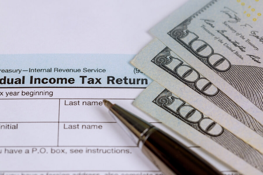 Income taxes receivable - Tax return form with dollar bills and a pen.