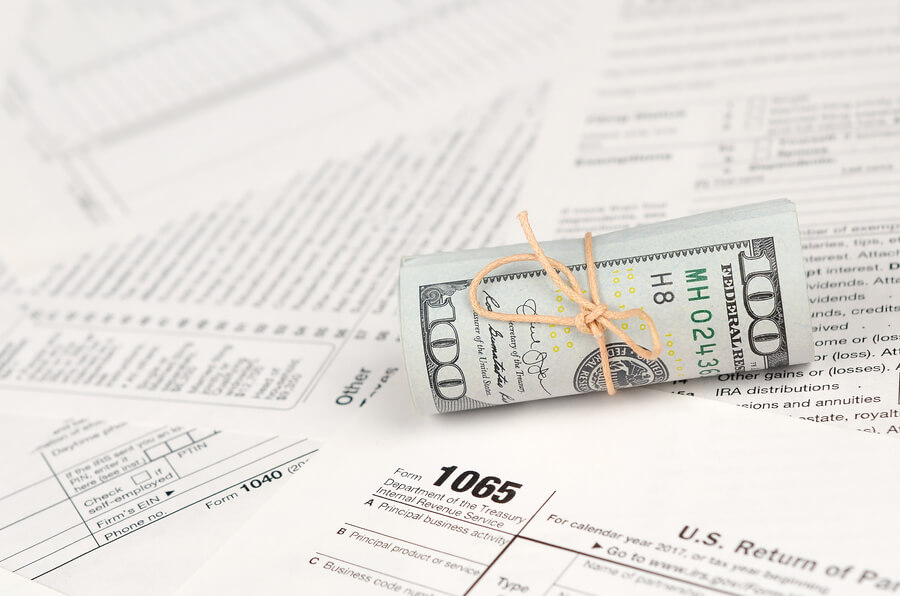Is income tax refund considered income - Rolled dollar bill on U.S. tax forms.