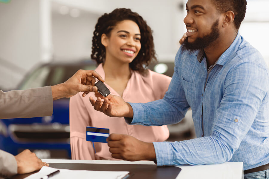 Customer receiving car keys from a sales consultant at a dealership.