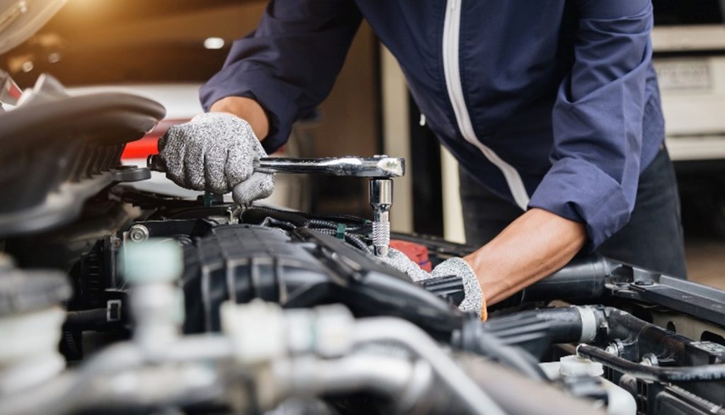 A mechanic working on an engine by Highgate Motors of Barrington