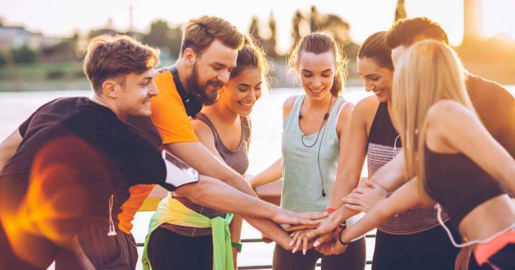 a group of athletes with their hands together showing how a buy here pay here dealership can be used to win