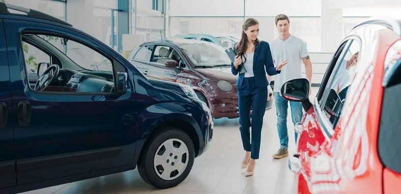 a woman at a buy here pay here dealership walking a man through her showroom floor