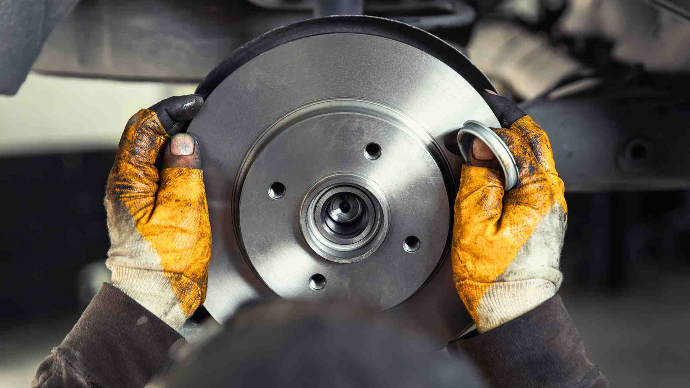 a technician's hands placing brakes onto a vehicle as he performs brake maintenance for used cars