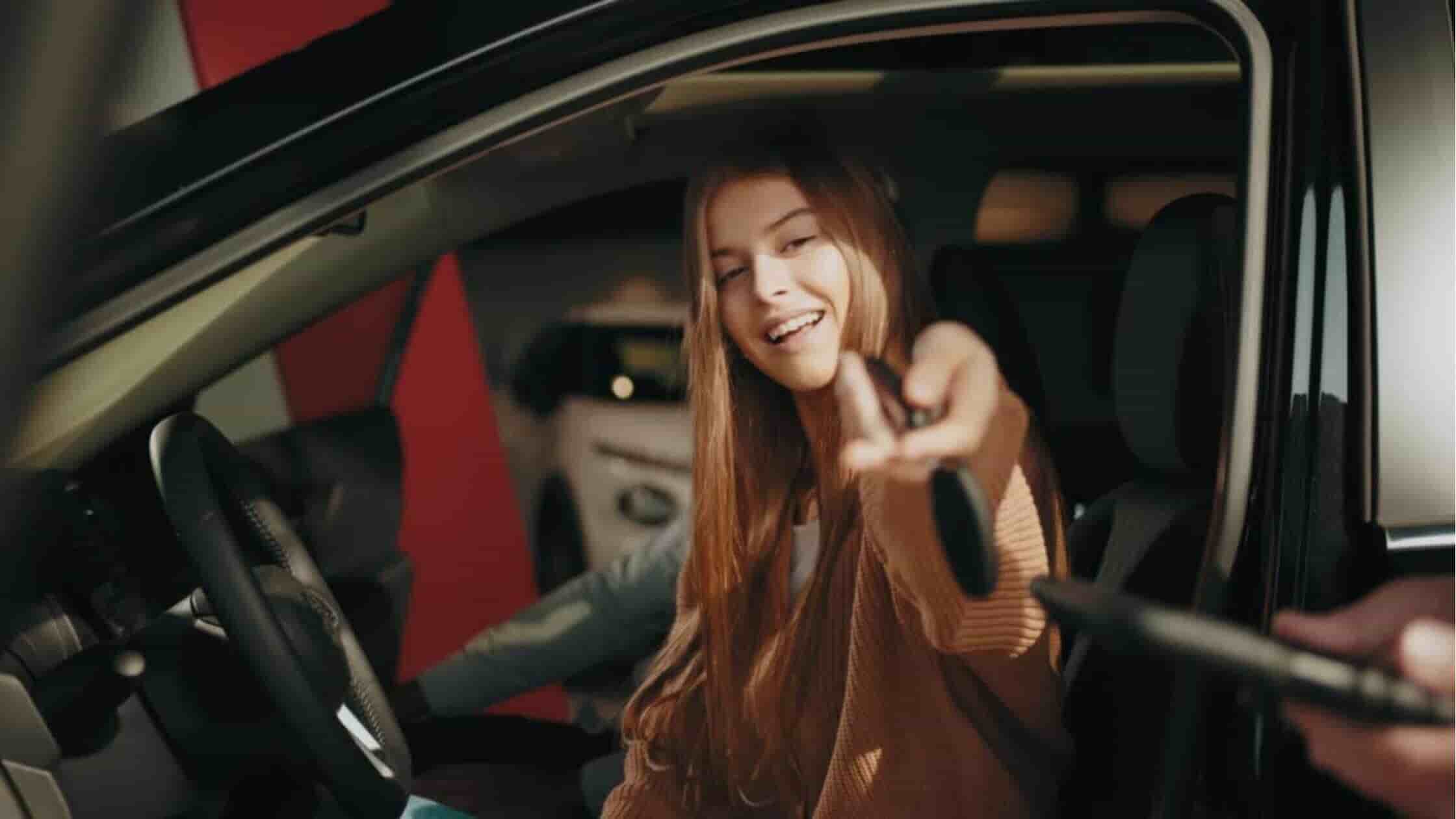 Happy woman proudly displaying the keys to her recently purchased used car from the best in house financing dealership for auto loans