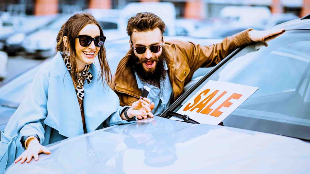 a happy couple swooning a car that says sale as if they got a bargain at a car auction