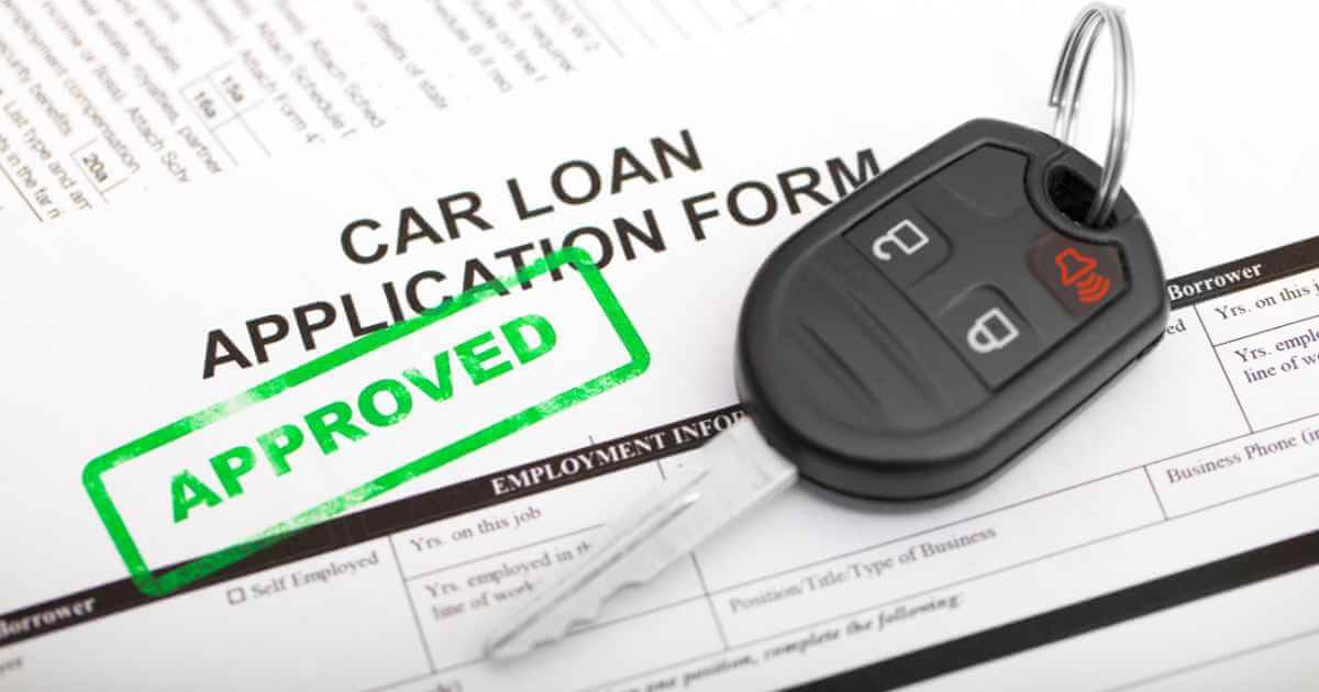 a key on top of a car loan application that shows you can get approved to buy a car after being denied an auto loan