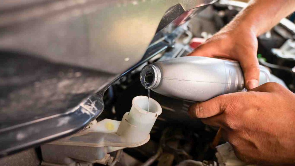 a mechanic pouring brake fluid into the reserovoir as he performs the routine brake maintenance for used cars