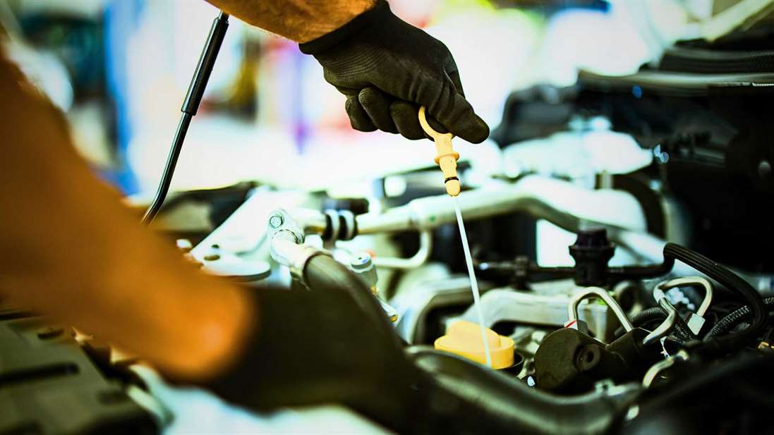 a man removing the dip stick for the engine oil to check if the used car needs an oil change