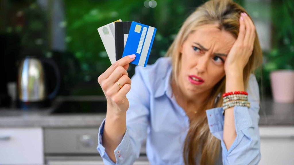 a woman frustrated with the credit cards she is holding up as she awaits financial freedom