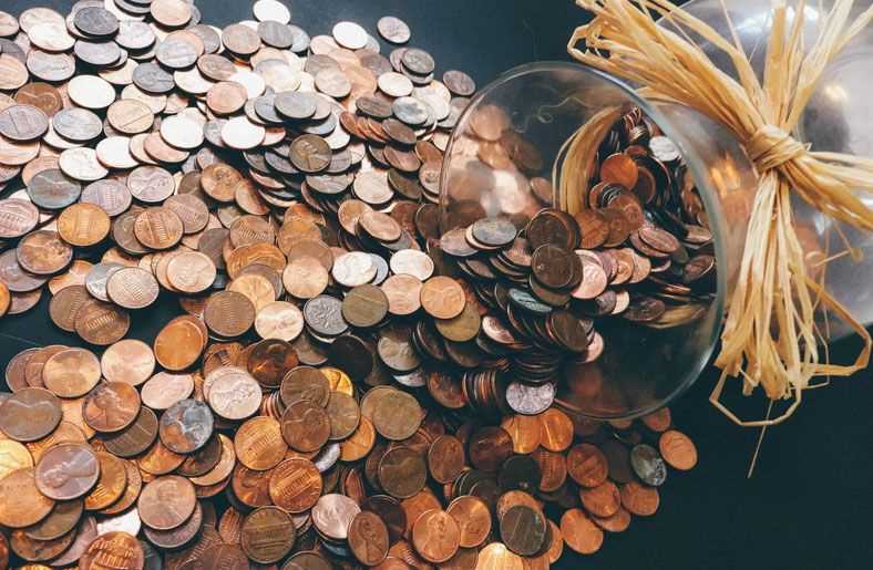 pennies falling out of a jar showing how saving is the fastest way to financial freedom