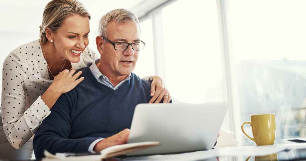 A man and woman looking at their laptop as they consider if low down payment cars for sale are right for them