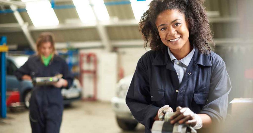 a happy woman working on a car part showing a successful car repair