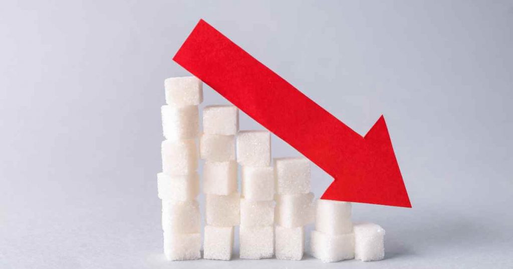 Cubes of sugar stacked up in a row with a bright red arrow pointing down showing the cons of low down payment cars for sale