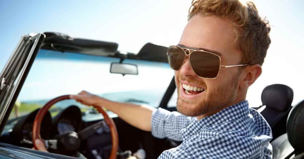 a man driving a car with a big grin on his face showing how easy buy a car at a car lot no license needed