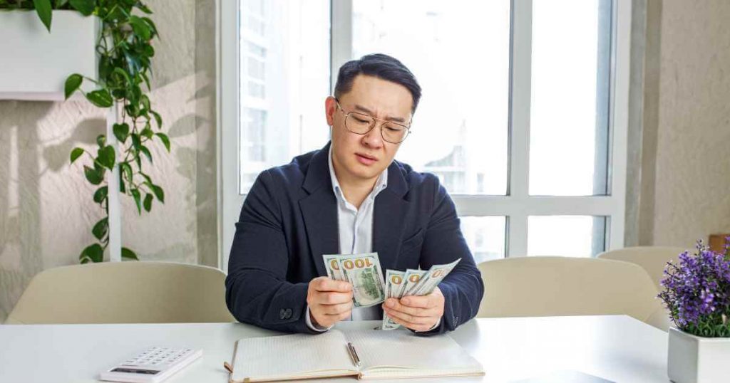 a man counting money with a confused look as he tries to understand