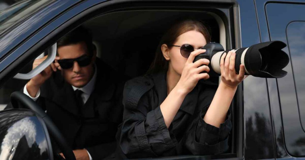 a man and woman inside of a car with a camera that has a long lens to allow them to zoom into finance here car dealerships