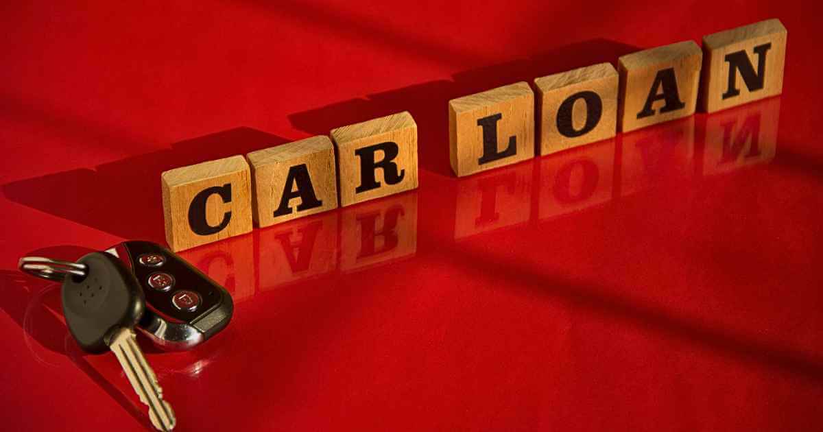 an image of a set of keys and blocks that read "car loans" on a deep red floor