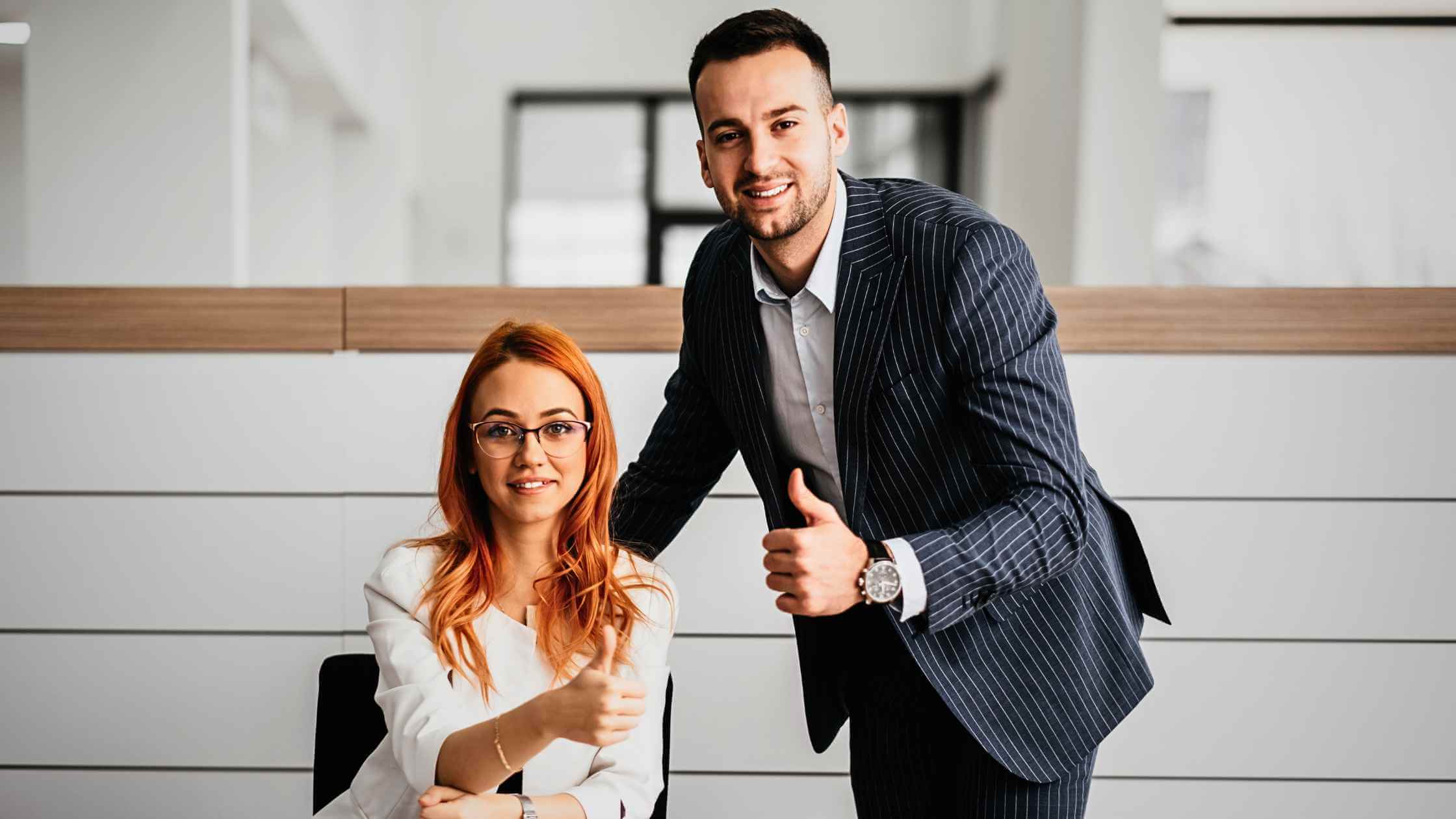 a photo of a man and woman smiling and holding their thumbs up as they secured the best car financing deals